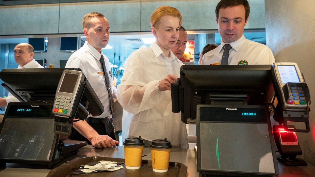 Mitarbeiter schauen auf die Kasse eines neu eröffneten Fast-Food-Restaurants in einer ehemaligen McDonald's in Moskau. Mitarbeiter schauen auf die Kasse eines neu eröffneten Fast-Food-Restaurants in einer ehemaligen McDonald's in Moskau.