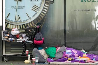 Eine Person schläft vor einem Rolex-Schaufenster: Wegen weltweit wachsender Armut fordert die UN reiche Länder zum Handeln auf.