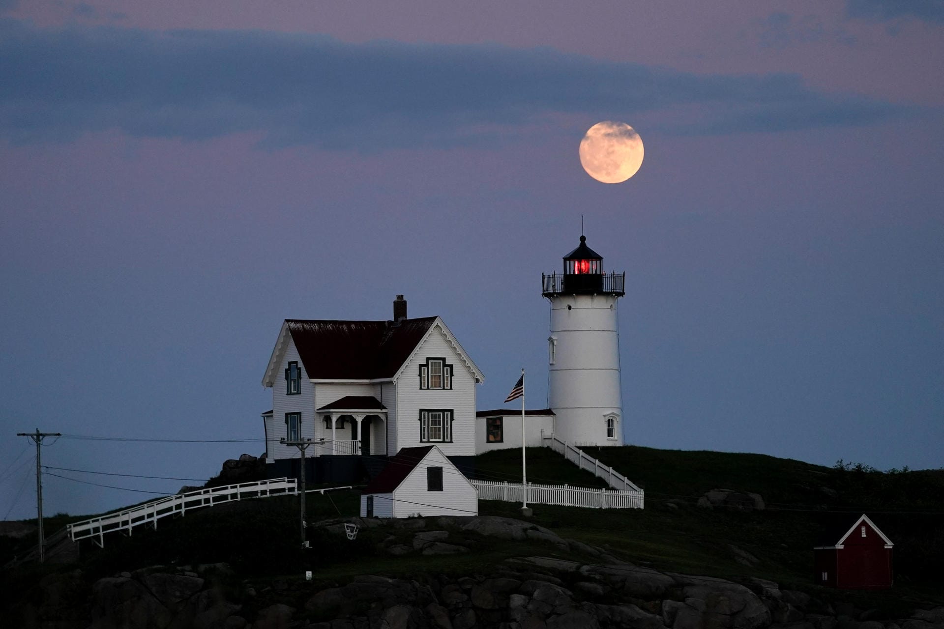 Ein zunehmender Mond geht über dem Cape Neddick Leuchtturm auf.