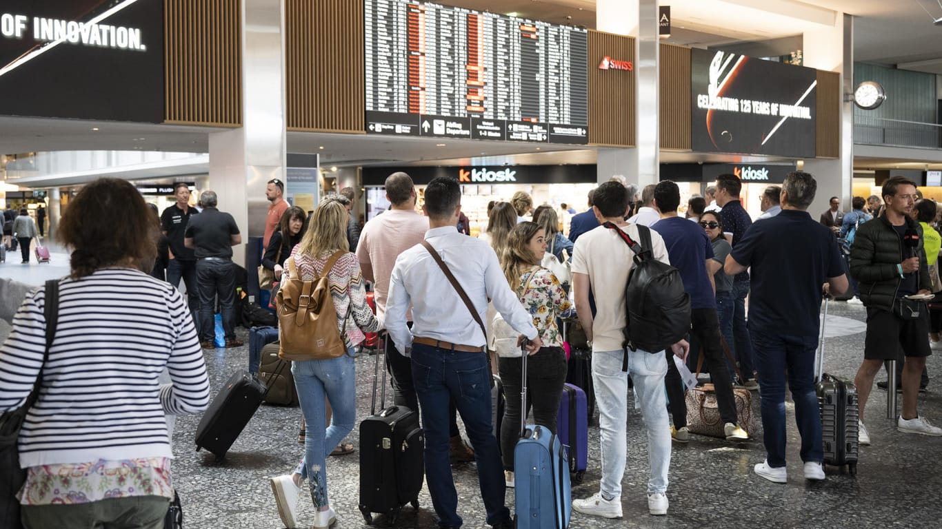 Fluggäste warten vor einer Anzeigetafel auf dem Flughafen in Zürich: Viele Flüge fallen aus oder werden verschoben.