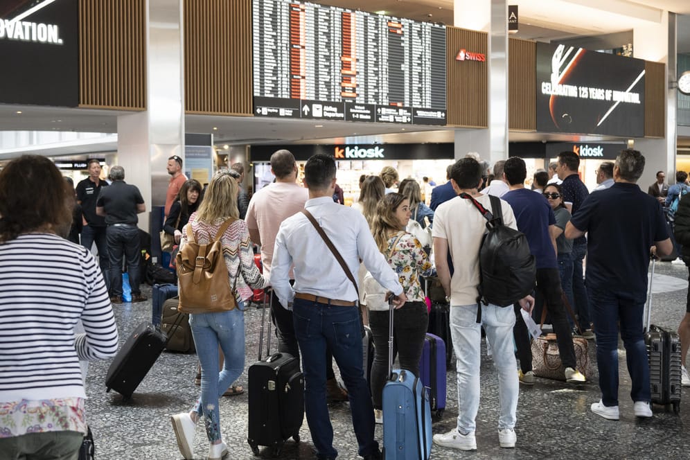 Fluggäste warten vor einer Anzeigetafel auf dem Flughafen in Zürich: Viele Flüge fallen aus oder werden verschoben.