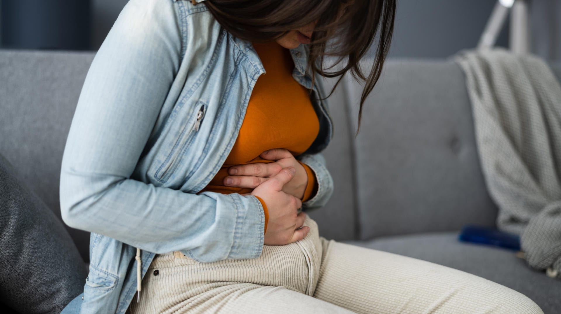 Frau hält sich den Bauch.