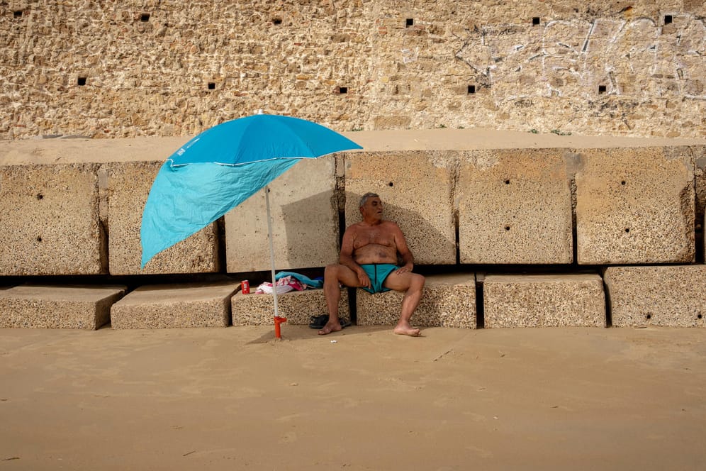 Cádiz in Spanien: In der südwestlich gelegenen Hafenstadt schützt sich ein Mann unter seinem Sonnenschirm vor der Hitze. Die höchsten Temperaturen wurden für Andalusien im Süden des Landes vorhergesagt.