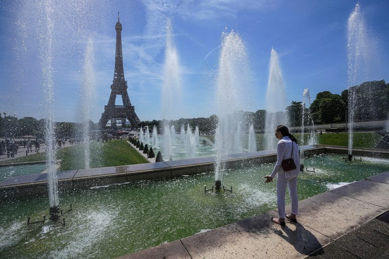 Eine Frau kühlt sich an einem Brunnen in Paris ab: In Frankreich müssen die Menschen sich örtlich auf Temperaturen bis zu 42 Grad einstellen.
