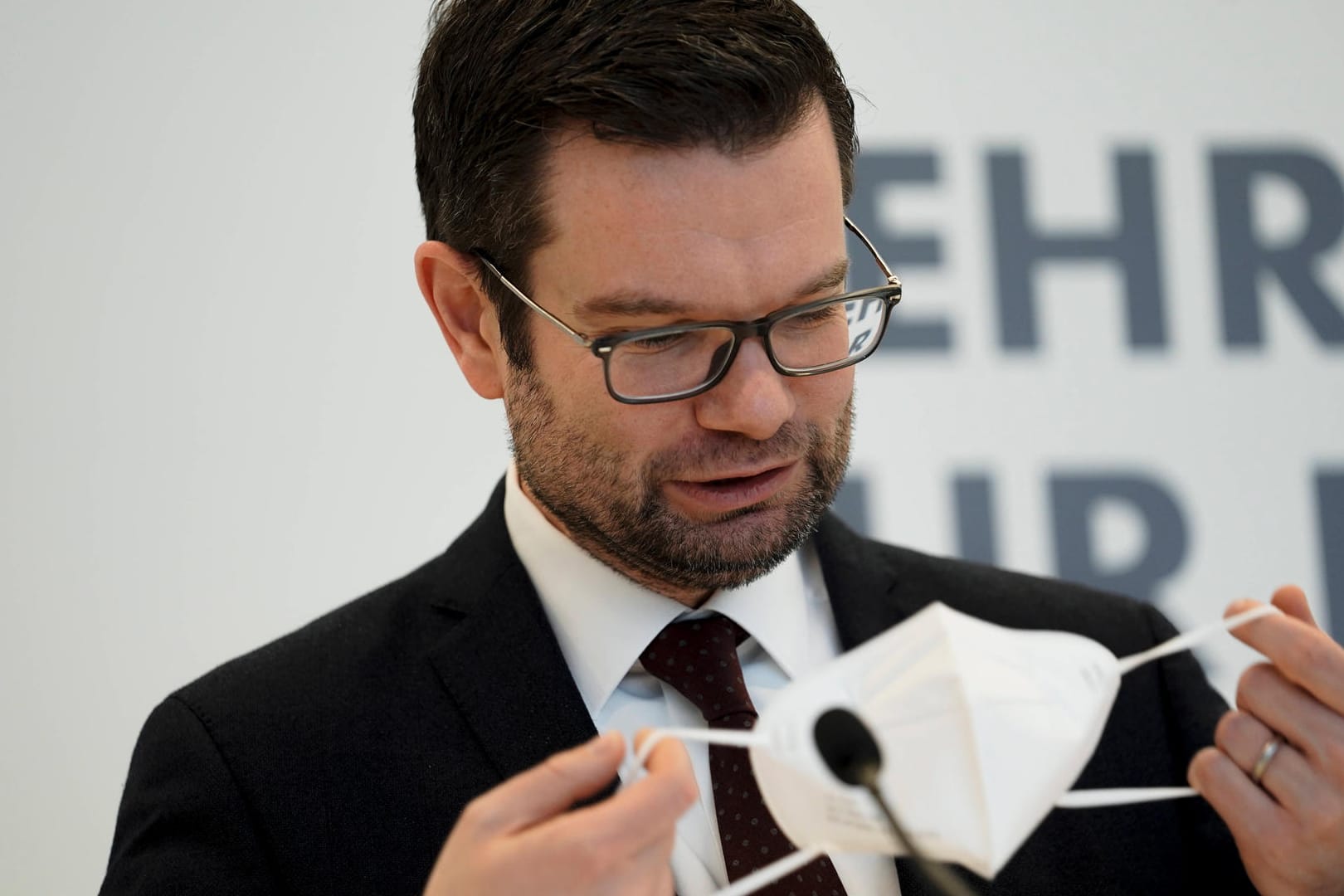 Marco Buschmann hält eine Maske in der Hand (Archivbild): Der Justizminister fordert weitere Gutachten, bevor er eine Maskenpflicht entscheiden will.