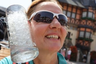 Eine Frau kühlt sich mit einem Glas voller Eiswürfel ab: Das heiße Wetter führte am Wochenende zu neuen Hitzerekorden in Sachsen.