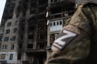 Ein russischer Soldat steht vor einem ausgebrannten Haus (Archivbild): Die Situation im Donbass spitzt sich zu.