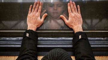 Ein Vater und seine Tochter halten die Hände an ein Zugfenster: Viele Familien wurden durch den Krieg in der Ukraine getrennt.
