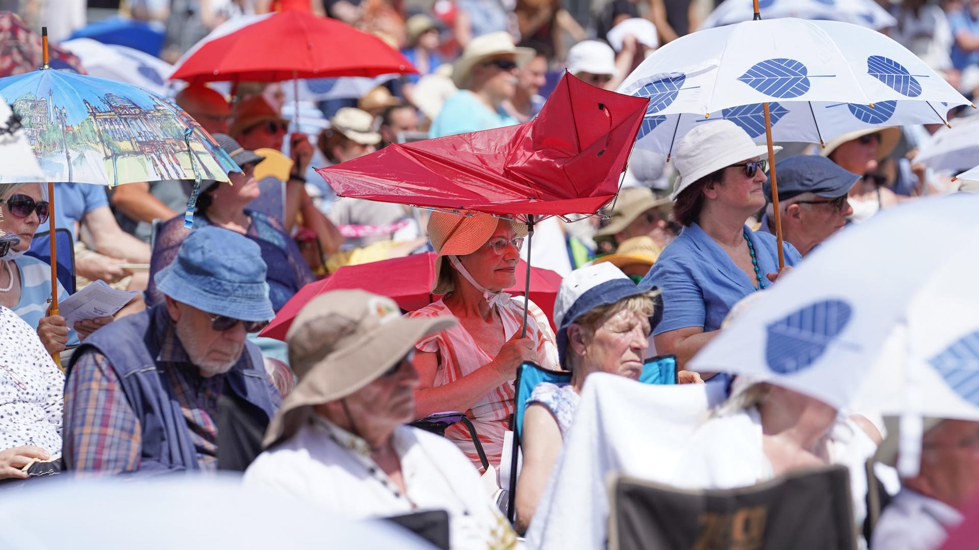 Auf dem Auf dem Bebelplatz vor der Berliner Staatsoper brennt die Sonne: Die Besucherinnen und Besucher eines Konzerts schützen sich mit Schirmen vor der Hitze.vor der Berliner Staatsoper brennt die Sonne: Die Besucherinnen und Besucher eines Konzerts schützen sich mit Schirmen vor der Hitze.