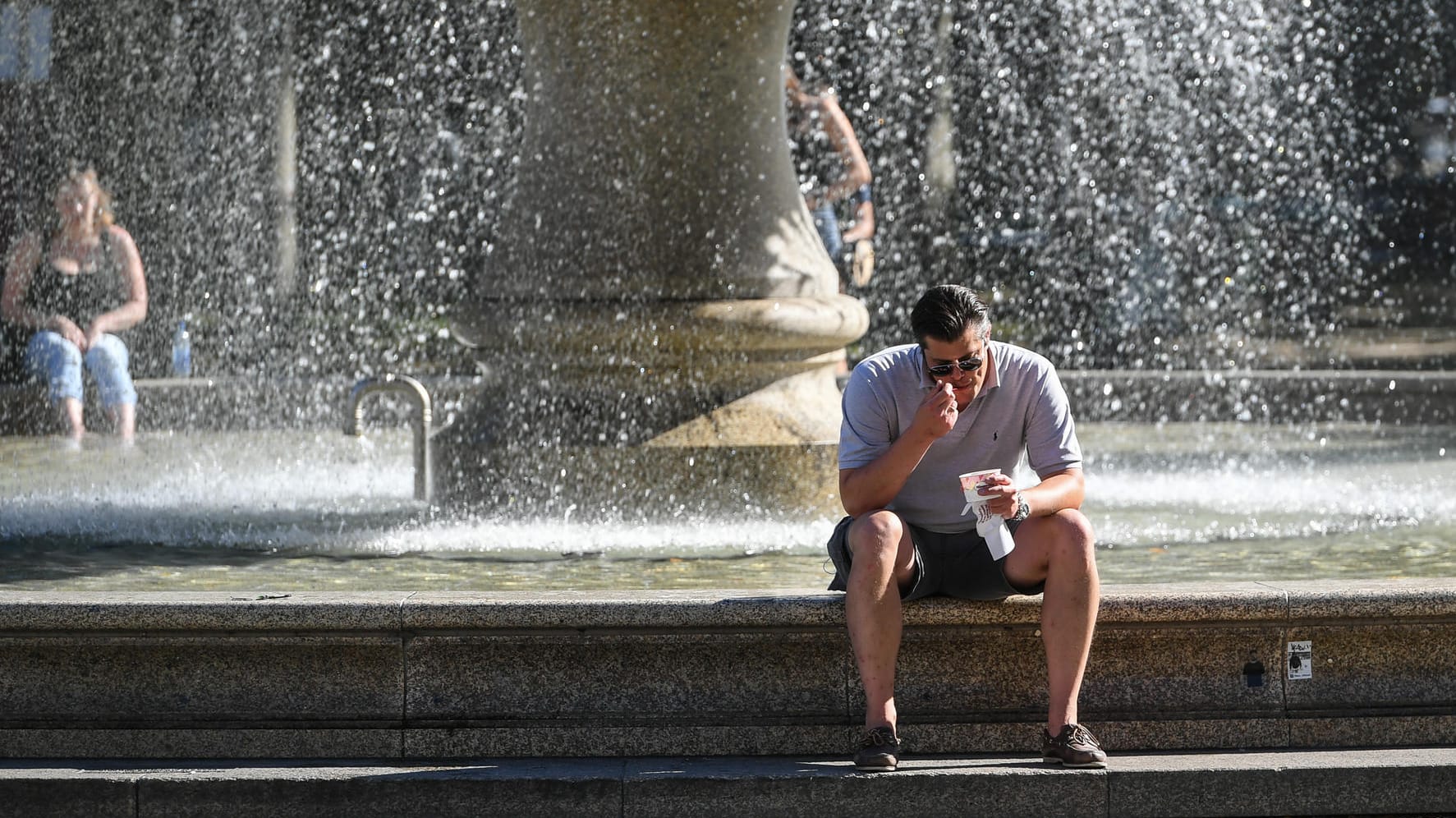 Kleine Abkühlung am Springbrunnen in Frankfurt am Main: Versiegelte Böden, dichte Bebauung und wärmespeichernde Fassaden treiben die Temperaturen in Innenstädten noch höher.