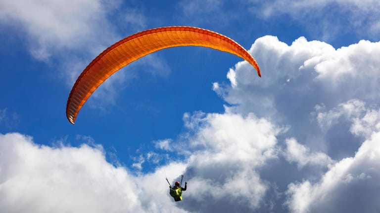 Ein Paragleiter schwebt durch den Wolkenhimmel (Symbolbild): Immer wieder kommt es zu tödlichen Unfällen bei dem Sport.