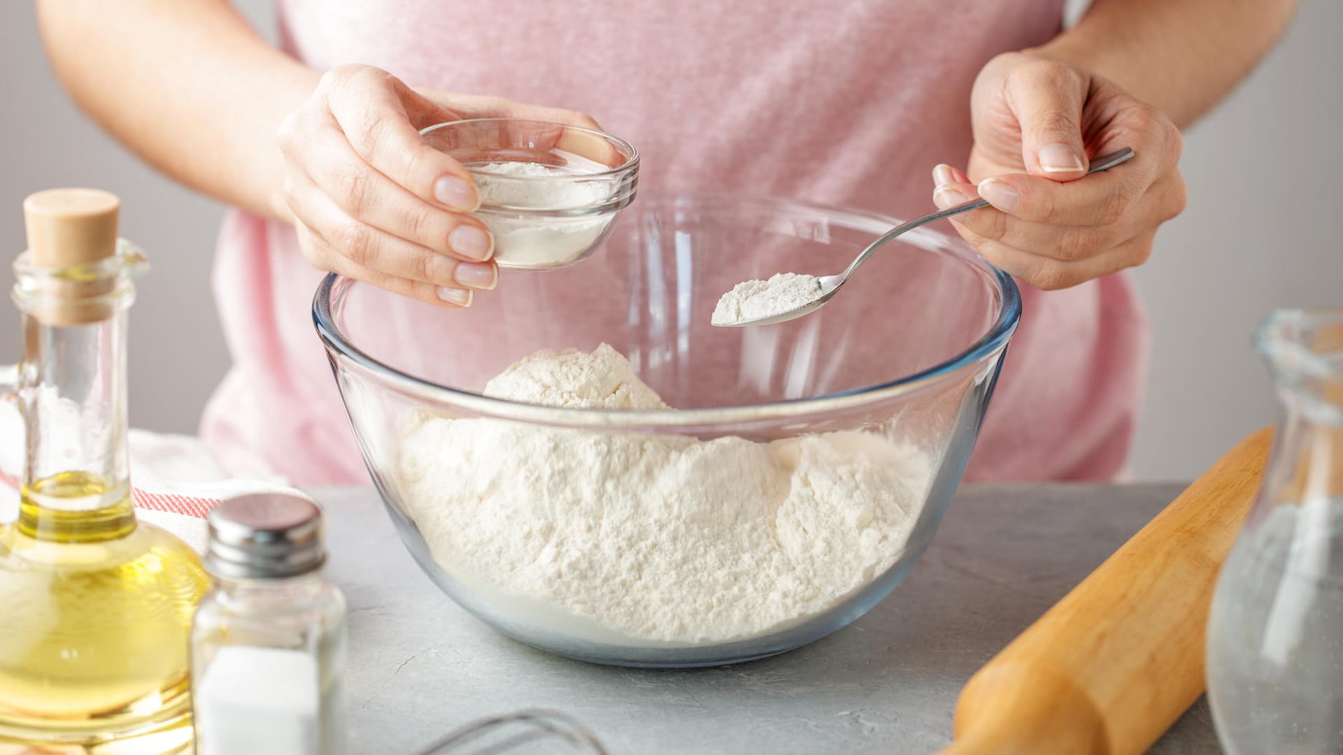 Frau fügt Backpulver zu Mehl hinzu: Reiner Natron in Kombination mit Zitronensaft ist eine gute Alternative zu Backpulver.