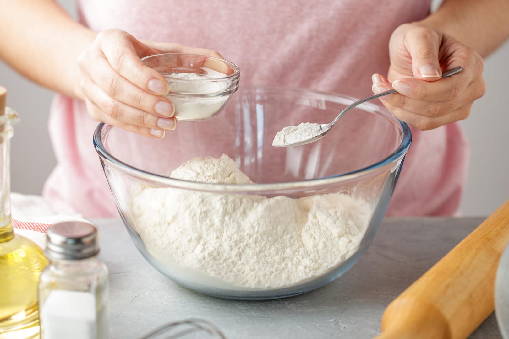 Frau fügt Backpulver zu Mehl hinzu: Reiner Natron in Kombination mit Zitronensaft ist eine gute Alternative zu Backpulver.