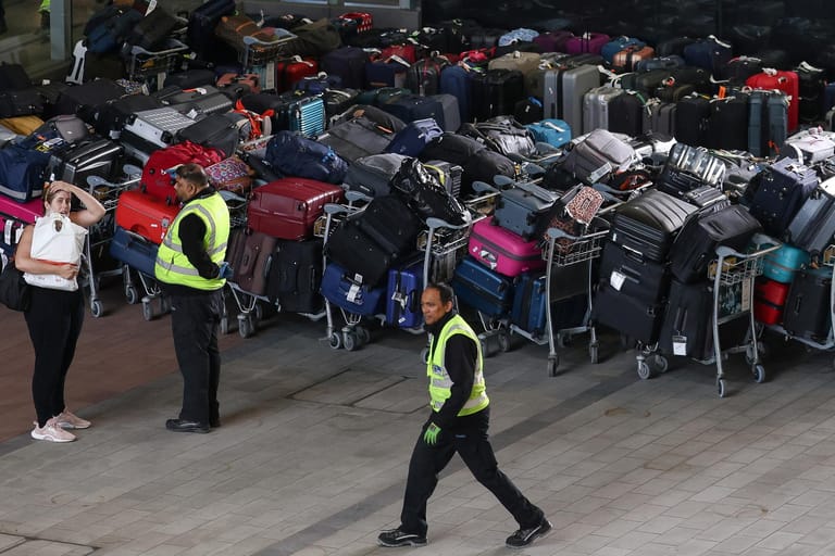 Eine Reisende und zwei Mitarbeiter im Terminal 2 des Flughafens Heathrow: Dort stauen sich seit Tagen die Koffer.