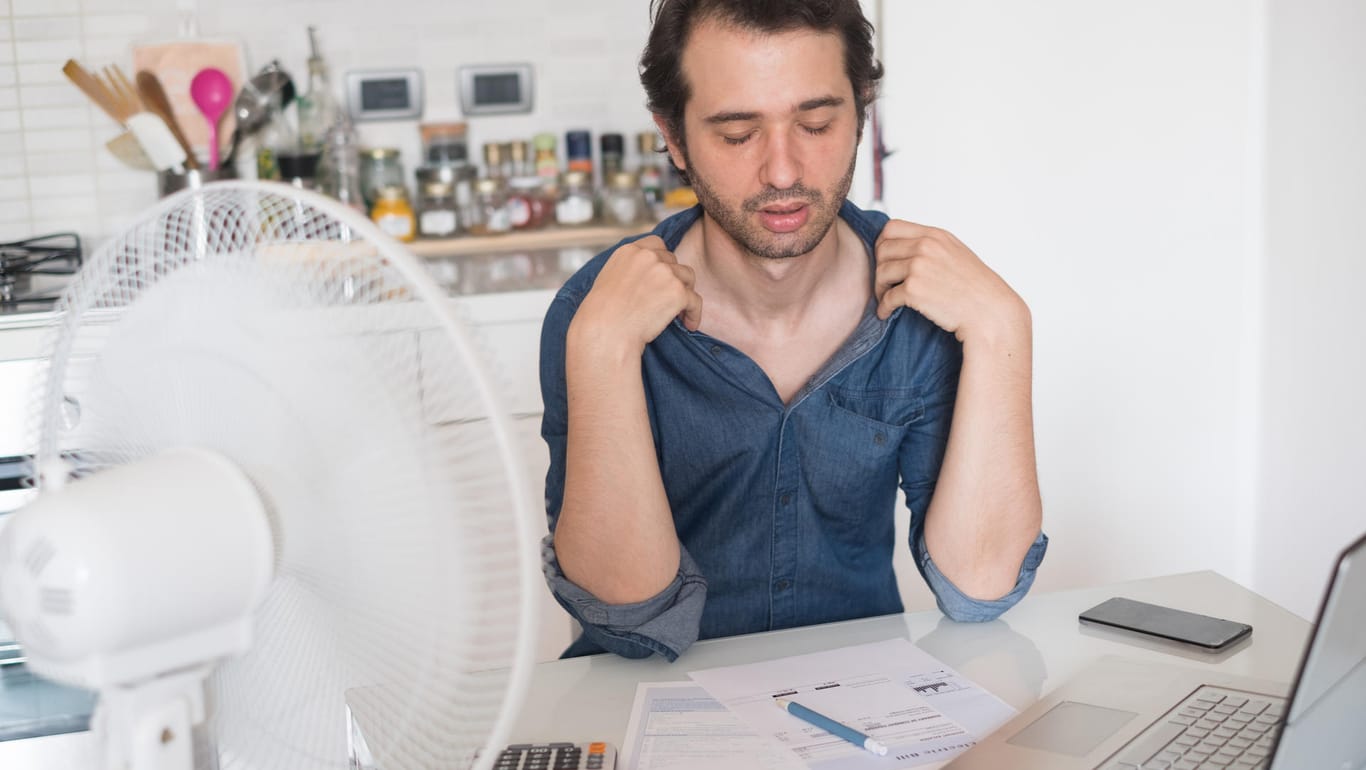 Sweaty man trying to refresh from heat with a fan (tommaso79)