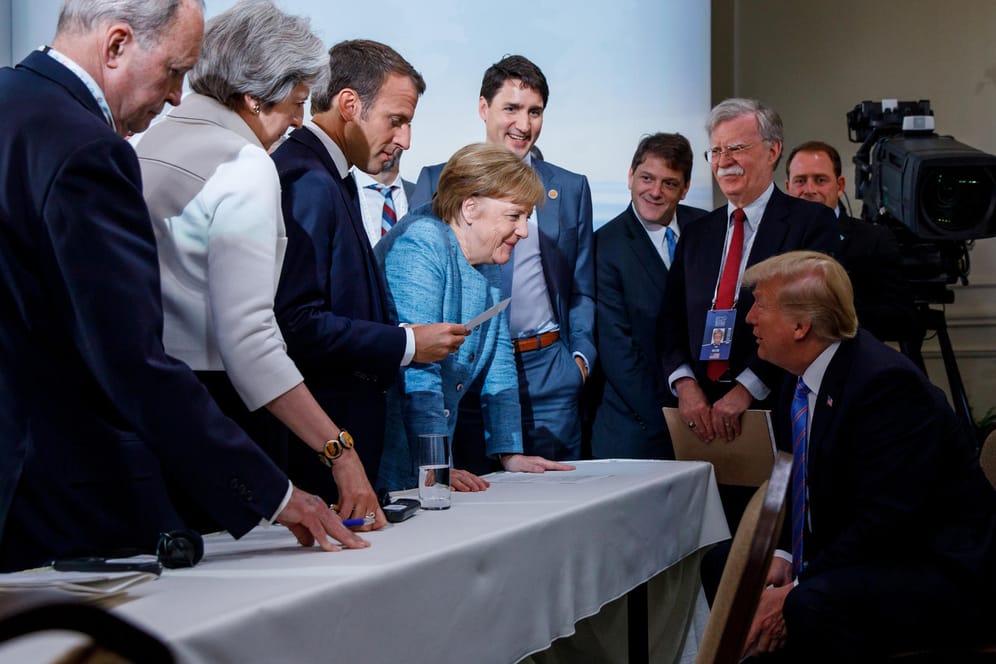 Angela Merkel und Donald Trump, umgeben von Kanadas Premier Justin Trudeau, der britischen Regierungschefin Theresa May und Frankreichs Präsident Emmanuel Macron: Verschiedene Versionen dieses Bildes gingen um die Welt. Es soll bei einem inoffiziellen Treffen zwischen zwei Tagesordnungspunkten des Gipfels in Kanada 2018 entstanden sein.