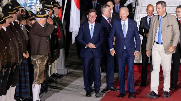 Joe Biden (M), Präsident der USA, geht mit Markus Söder (r, CSU), Ministerpräsident von Bayern, an bayerischen Gebirgsschützen und Trachtlern vorbei.