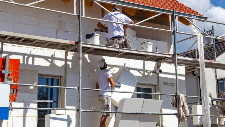 Bauarbeiter isolieren eine Hausfassade: Die Aussichten in der Baubranche haben sich eingetrübt.