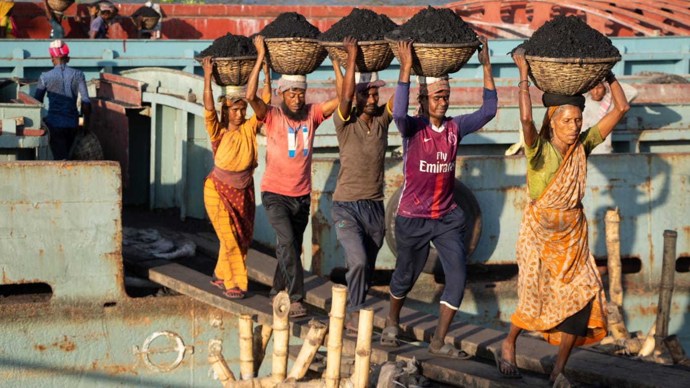 Arbeiterinnen und Arbeiter entladen einen Kohlefrachter im Hafen von Dhaka, Bangladesh: Vor allem in Süd- und Südostasien sind viele Schwellenländer noch stark von Kohle abhängig.