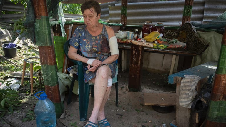 Bachmut in der Ukraine: Eine Frau sitzt im Hof ihres durch Beschuss durch das russische Militär beschädigten Hauses.