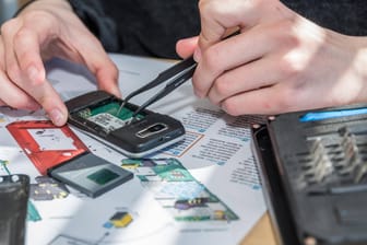 Techniker zerlegt altes Handy (Symbolbild): Insbesondere Kobalt, Silizium, Magnesium und Lithium sind wichtige Mineralien für Technologien.