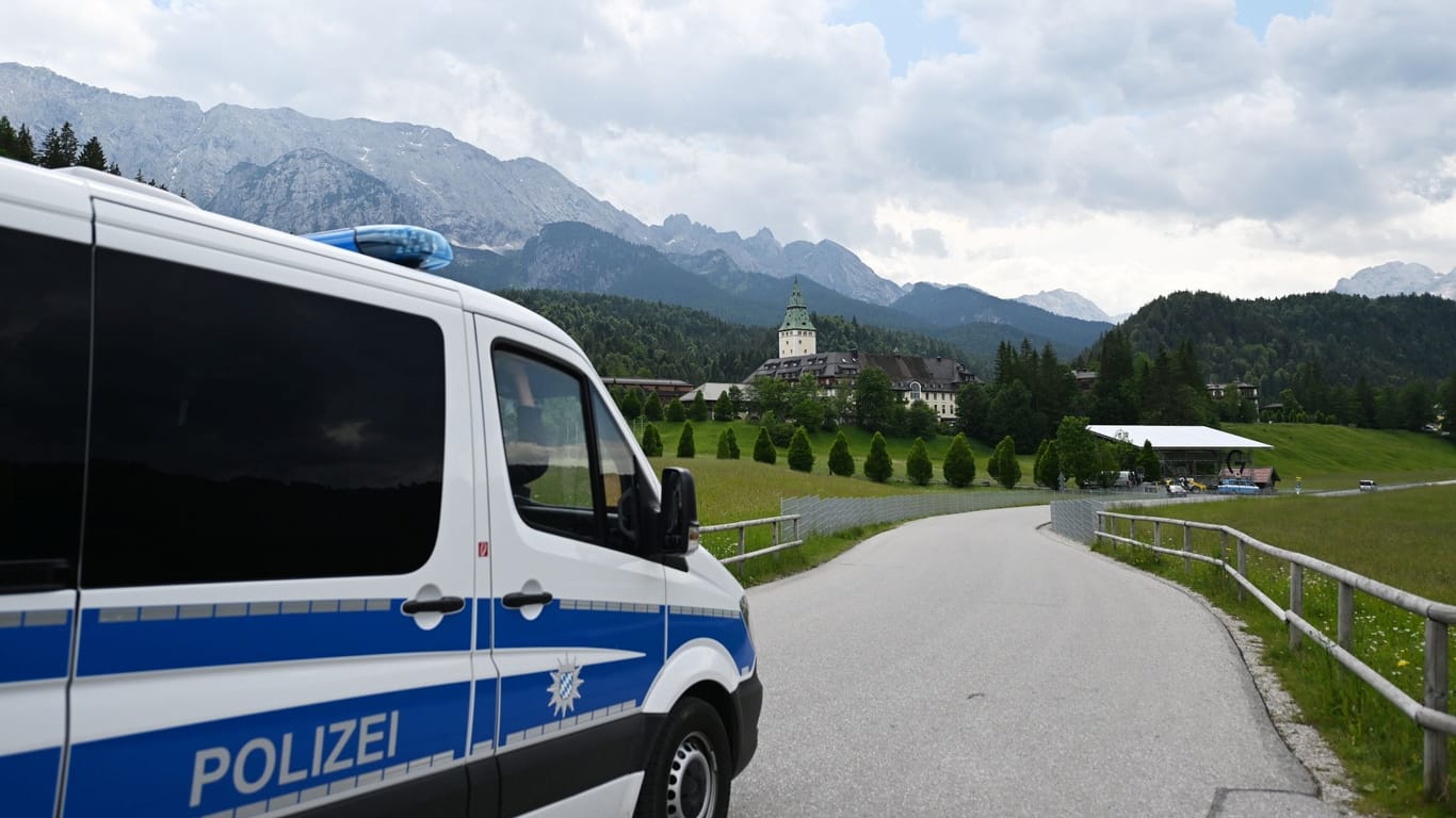 Ein Polizeiauto fährt auf das Schloss Elmau zu (Symbolbild): Insgesamt 15 Personen wurden in Gewahrsam genommen.