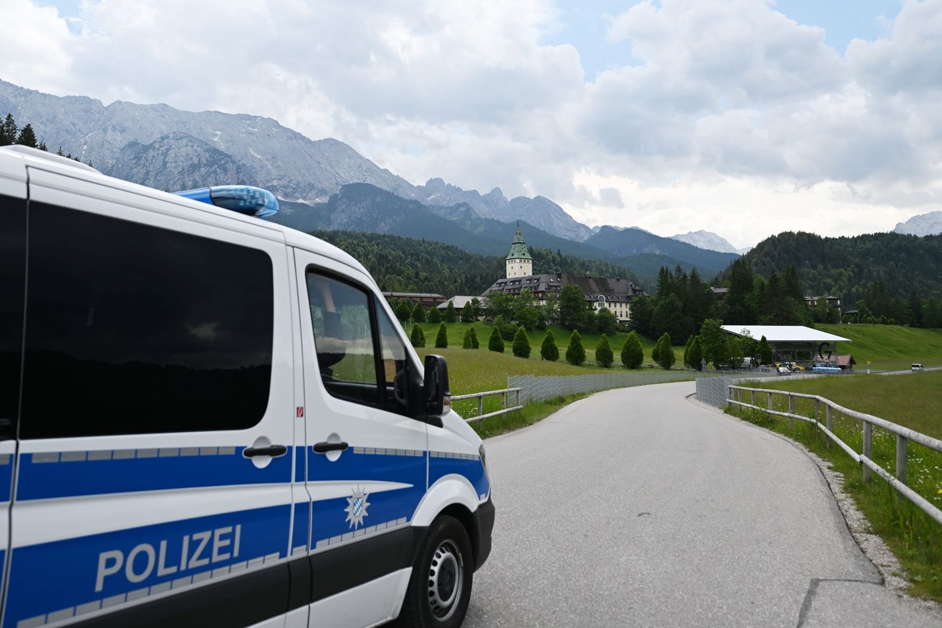 Ein Polizeiauto fährt auf das Schloss Elmau zu (Symbolbild): Insgesamt 15 Personen wurden in Gewahrsam genommen.