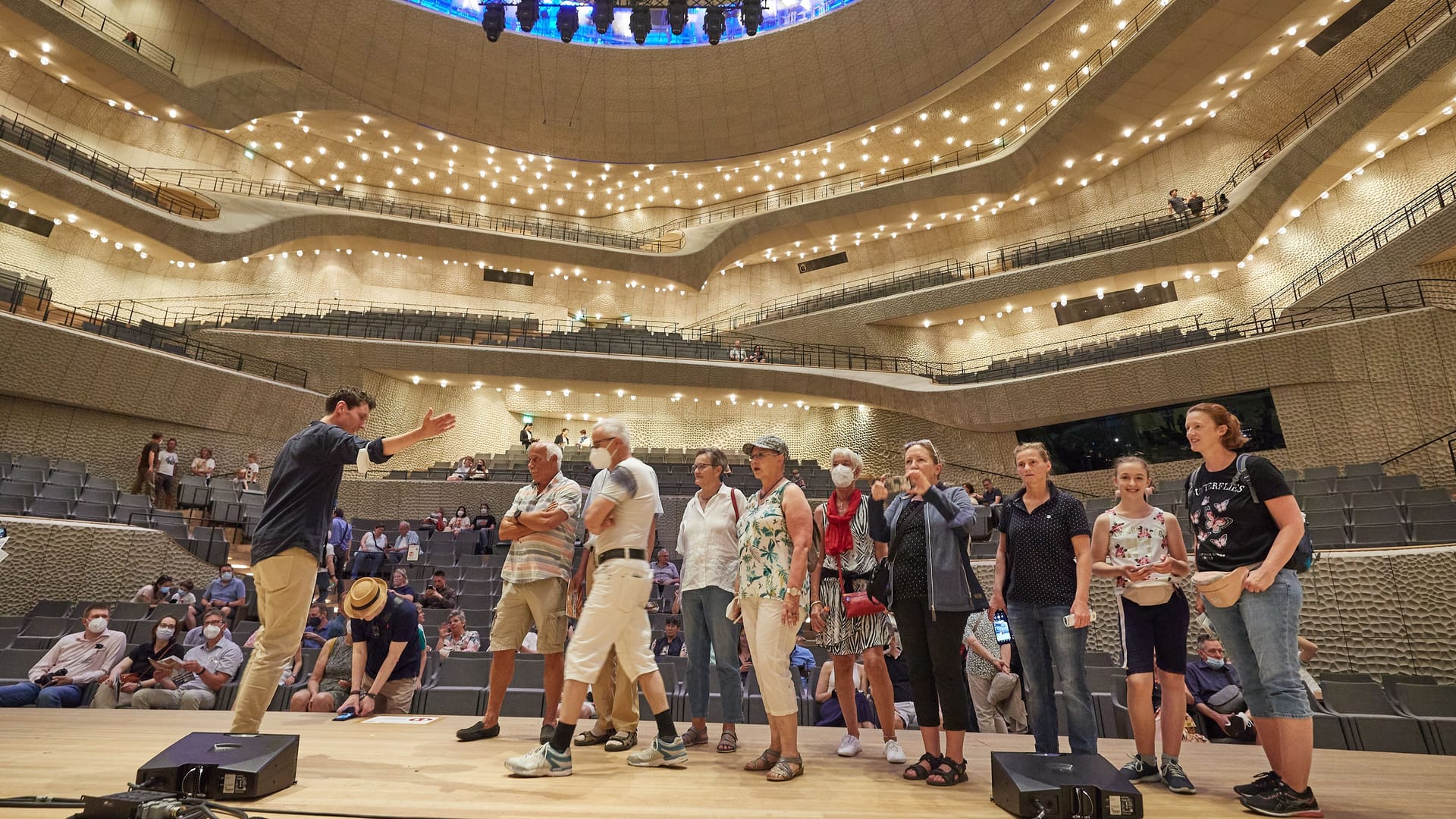 Alan Schuler (l), Projektleiter, steht zusammen mit Besuchern während einer Führung am Tag der offenen Tür in der Elbphilharmonie auf der Bühne im Großen Saal. Alan Schuler (l), Projektleiter, steht zusammen mit Besuchern während einer Führung am Tag der offenen Tür in der Elbphilharmonie auf der Bühne im Großen Saal.