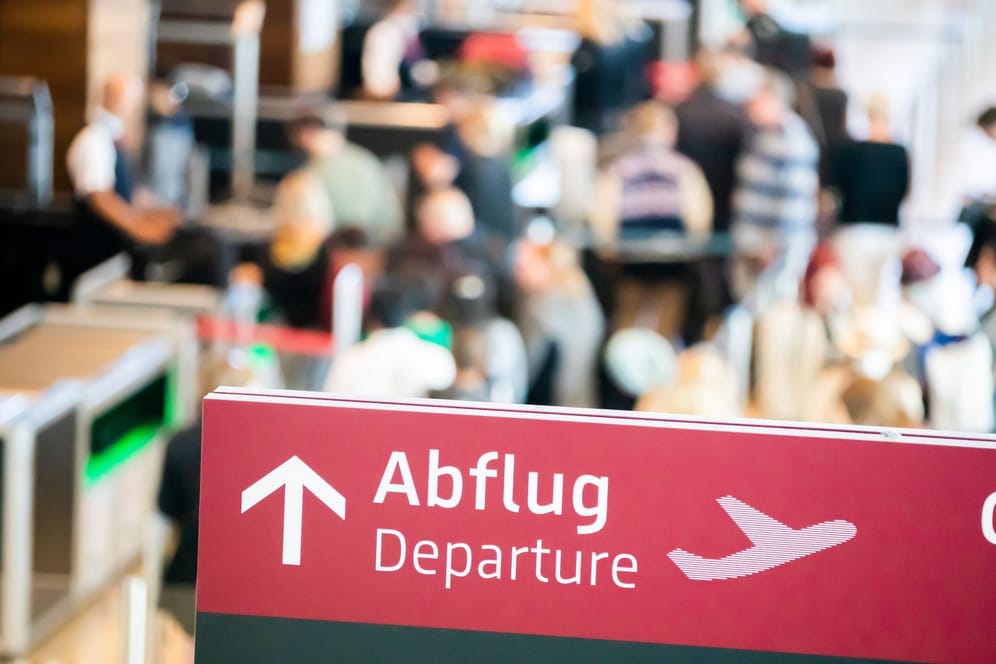Menschen stehen am Flughafen Berlin Brandenburg (BER) an der Sicherheitskontrolle (Archivbild): Die Sommerferien stehen kurz bevor.