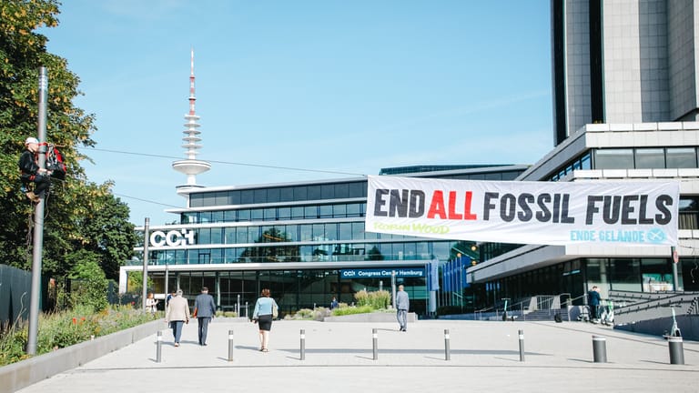 Ein Aktivist hängt an einem Laternenmast vor dem Congress Center Hamburg, an dem ein Banner befestigt ist: Am Mittwochmorgen kam es zu einer Protestaktion gegen Erdgas.