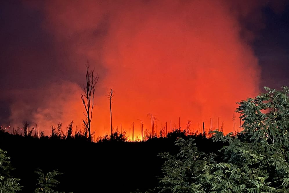 Rot erleuchtet ist der Nachthimmel durch das Feuer eines Waldbrands in der Nähe der brandenburgischen Kleinstadt Treuenbrietzen.