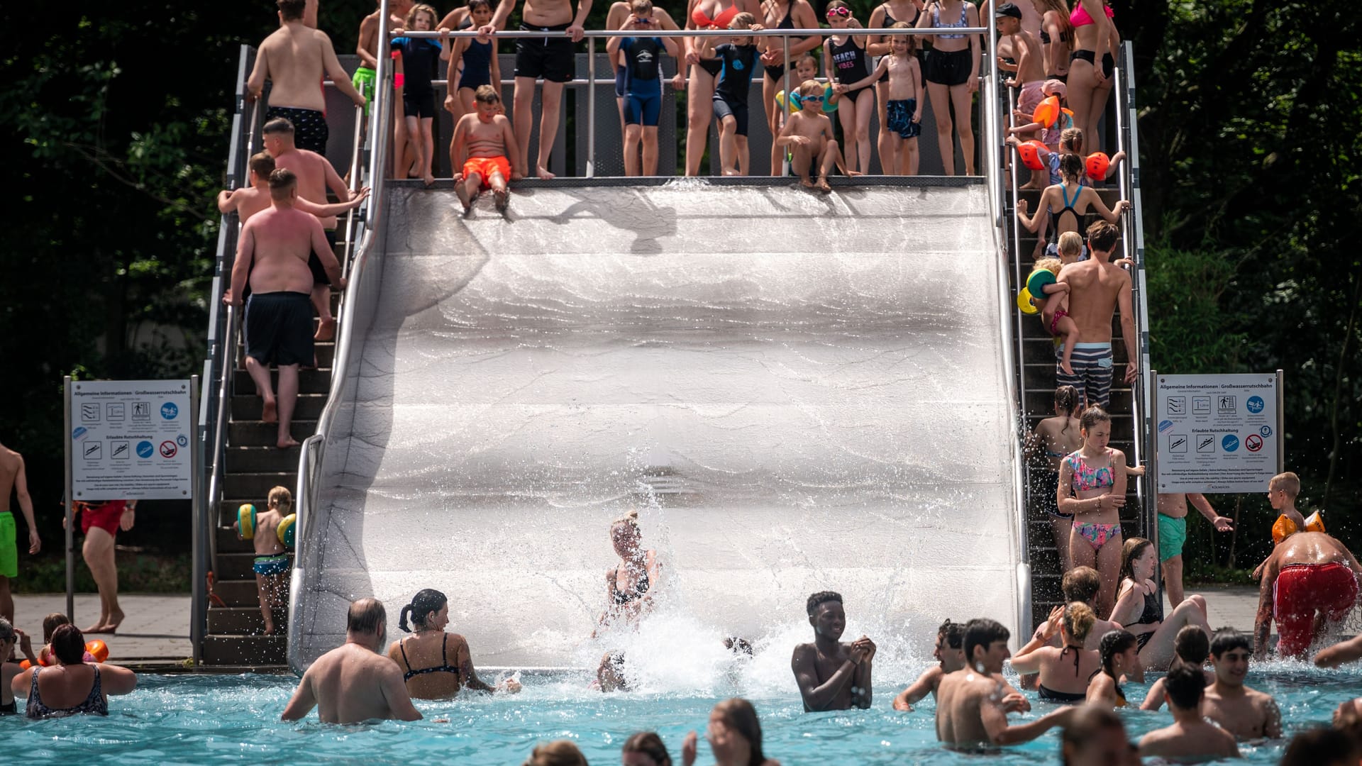 Badegäste stehen im Stadionbad an einer Rutsche.