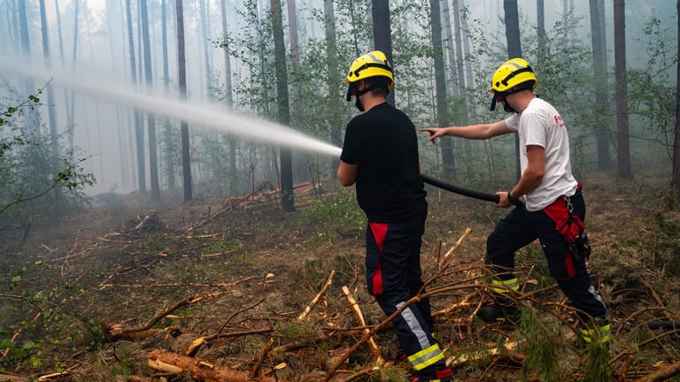 Feuerwehrleute bekämpfen die Flammen in Brandenburgs Wäldern: Immer wieder zerreißen Explosionen die hektische Betriebsamkeit.