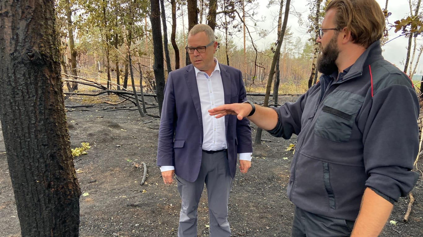 Brandenburgs Innenminister Michael Stübgen (links) begutachtet die Schäden der Waldbrände.