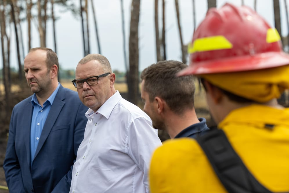 Michael Stübgen (Zweiter von links, CDU), Innenminister von Brandenburg, erkundigt sich bei den Einsatzkräften über den Waldbrand in der Gorischheide. Dieser ist am Samstag unter Kontrolle.