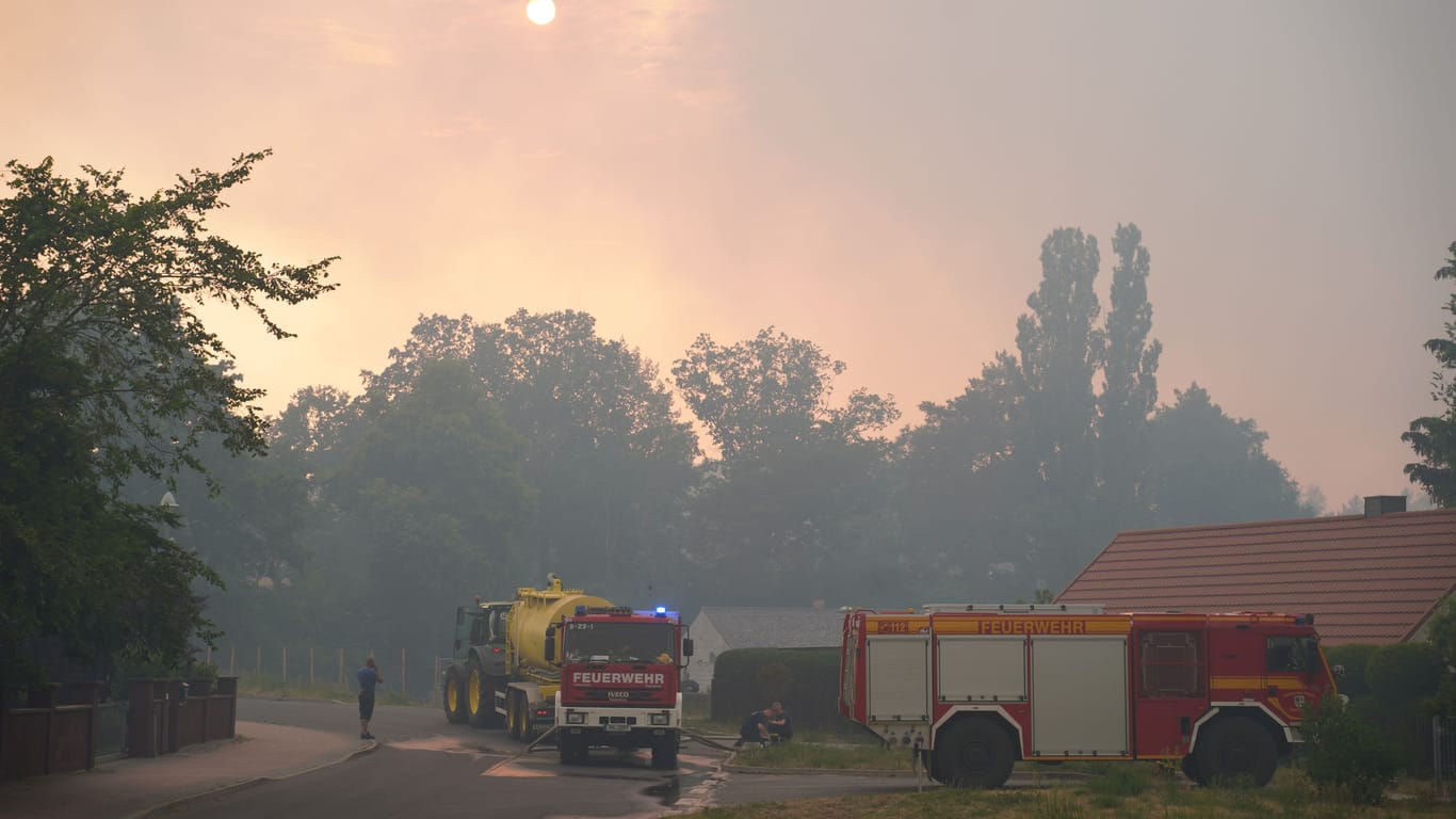 Einsatzfahrzeuge in Beelitz-Heilstätten: Dichter Rauch verdeckt die Sonne, die Rettungskräfte rüsten sich für die nächste Fahrt in die brennenden Wälder.