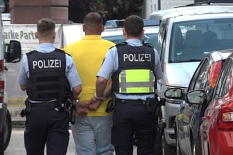 Polizisten nehmen einen Mann in Euskirchen fest: Bei mehreren Razzien in der Stadt wurden Geld, Drogen und Waffen beschlagnahmt.
