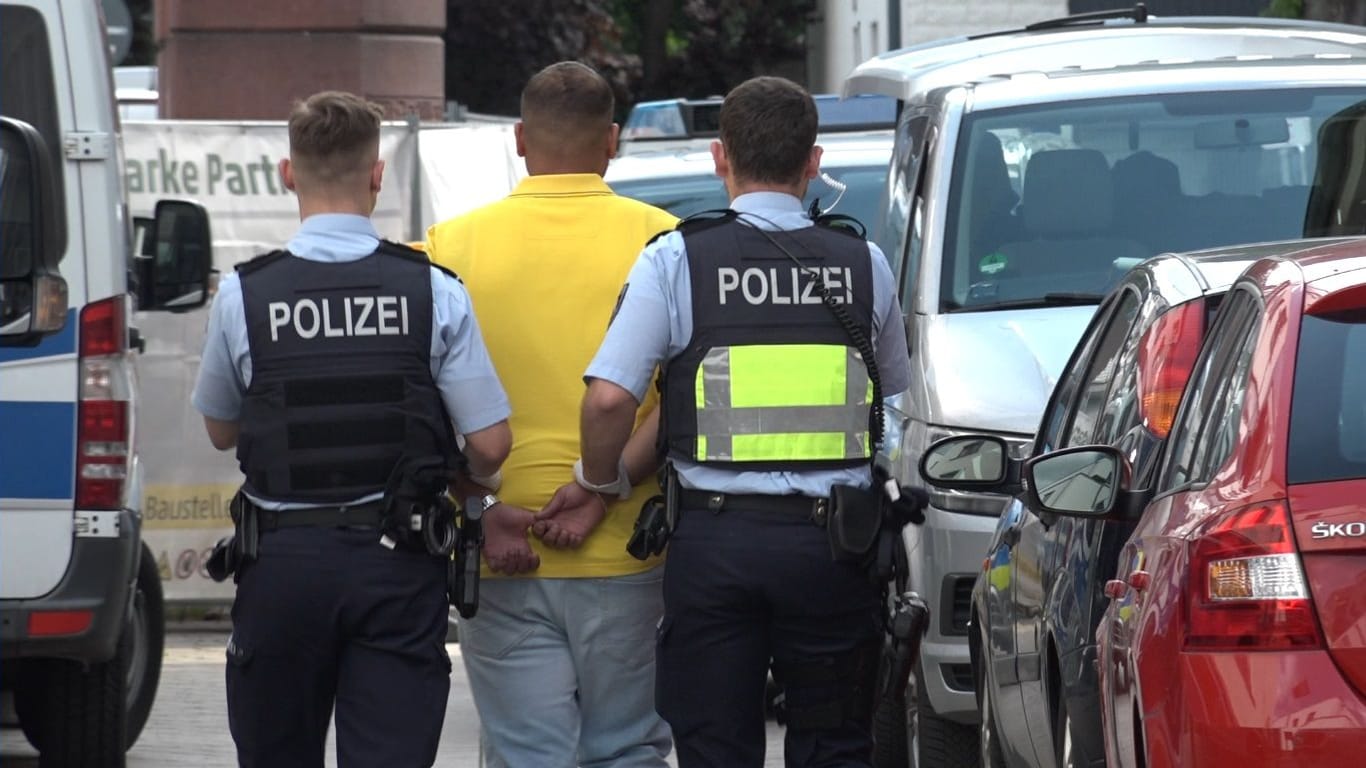 Polizisten nehmen einen Mann in Euskirchen fest: Bei mehreren Razzien in der Stadt wurden Geld, Drogen und Waffen beschlagnahmt.