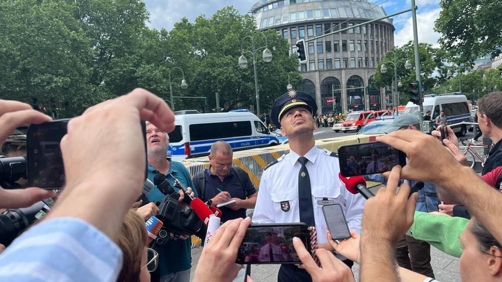 Polizeisprecher Cablitz bei einem Gespräch mit Journalisten vor Ort: Er beobachtet einen kreisenden Polizeihubschrauber.
