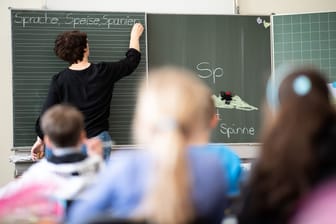 Eine Lehrerin schreibt Wörter auf eine Tafel (Symbolbild): So friedlich geht es an einer Bremer Grundschule offenbar nicht zu.