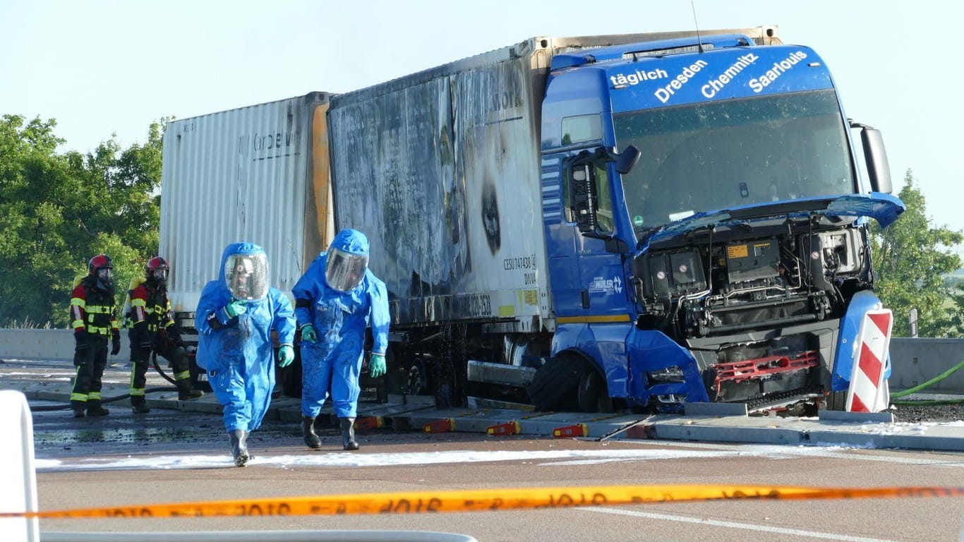 Einsatzkräfte neben dem ausgebrannten Lkw: Wie es zu dem Feuer kam, ist bisher noch unklar.