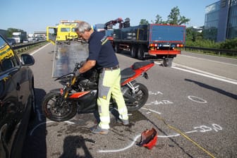 Aufräumarbeiten auf der Autobahn 81: Ein Helfer schiebt das Unfallmotorrad beiseite.