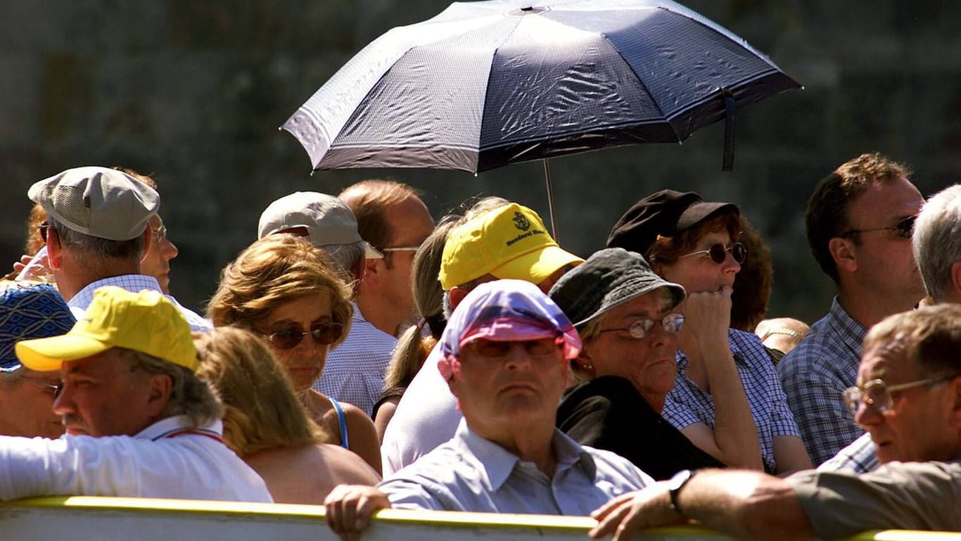 Touristen schützen sich gegen die brütende Hitze: Insbesondere ältere Menschen sind von der extremen Hitze gefährdet.