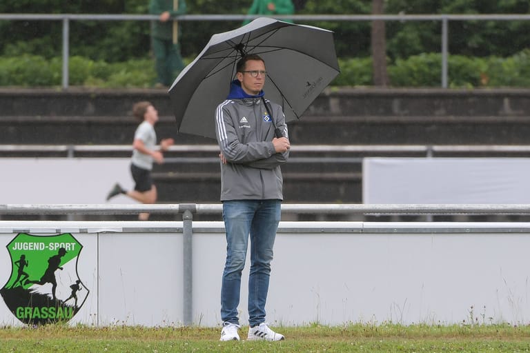 Ex-HSV-Sportdirektor Michael Mutzel steht mit Regenschirm an einem Fußballplatz (Archivbild): Kurz vor dem Saisonstart verkündet der Zweitligist die Trennung.