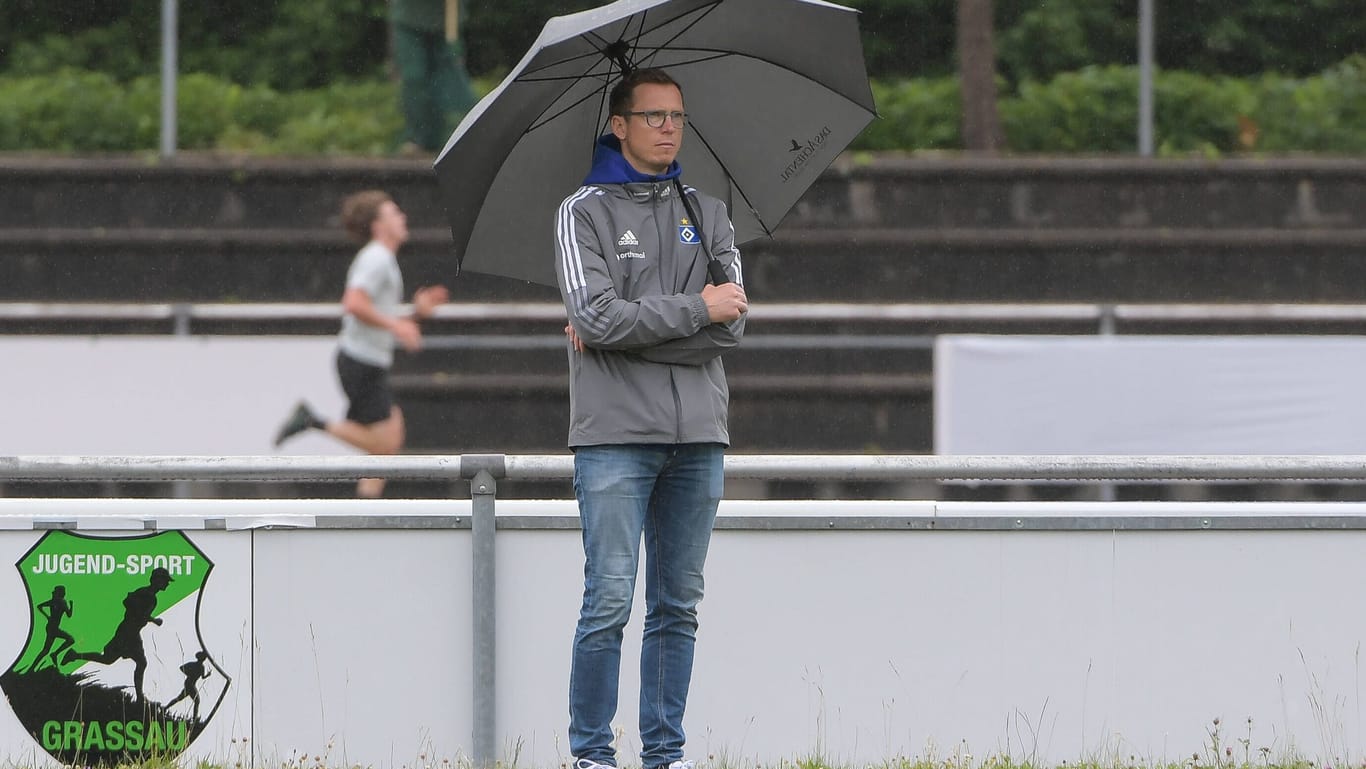 Ex-HSV-Sportdirektor Michael Mutzel steht mit Regenschirm an einem Fußballplatz (Archivbild): Kurz vor dem Saisonstart verkündet der Zweitligist die Trennung.