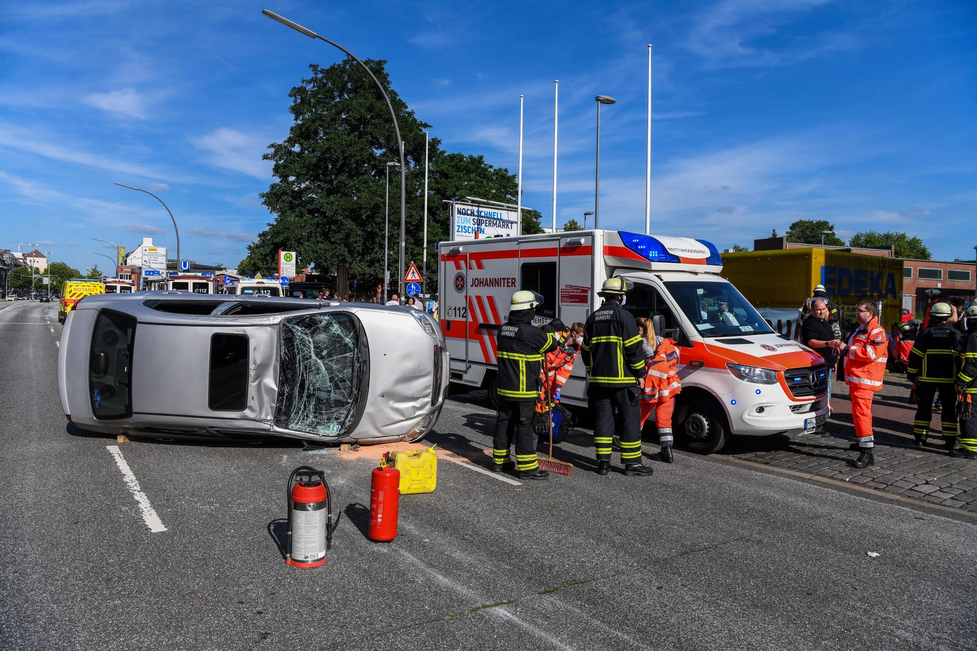 Der Unfallwagen liegt auf der Seite. Daneben stehen Rettungskräfte.