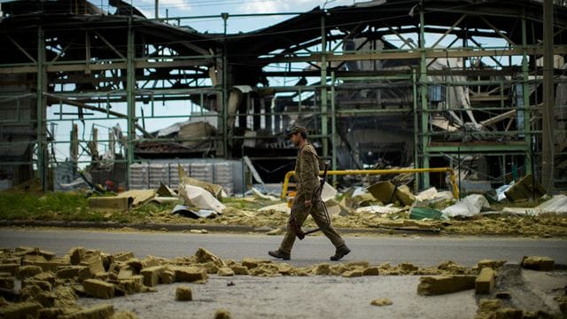 Ein ukrainischer Soldat geht an einer durch Beschuss zerstörten Fabrik vorbei.