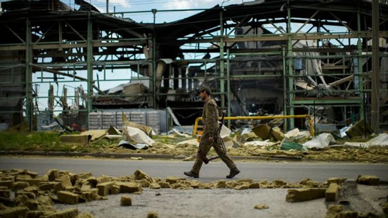 Ein ukrainischer Soldat geht an einer durch Beschuss zerstörten Fabrik vorbei.