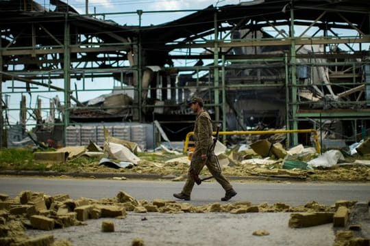 Ein ukrainischer Soldat geht an einer durch Beschuss zerstörten Fabrik vorbei.