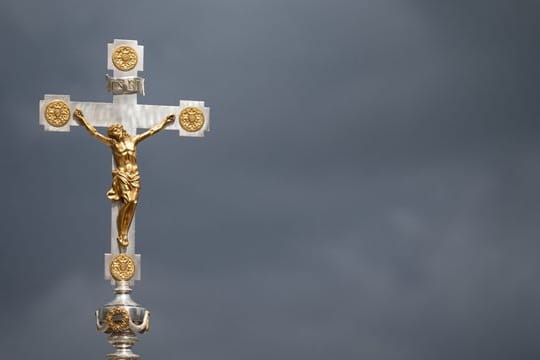 Ein Kruzifix vor dunklen Wolken.